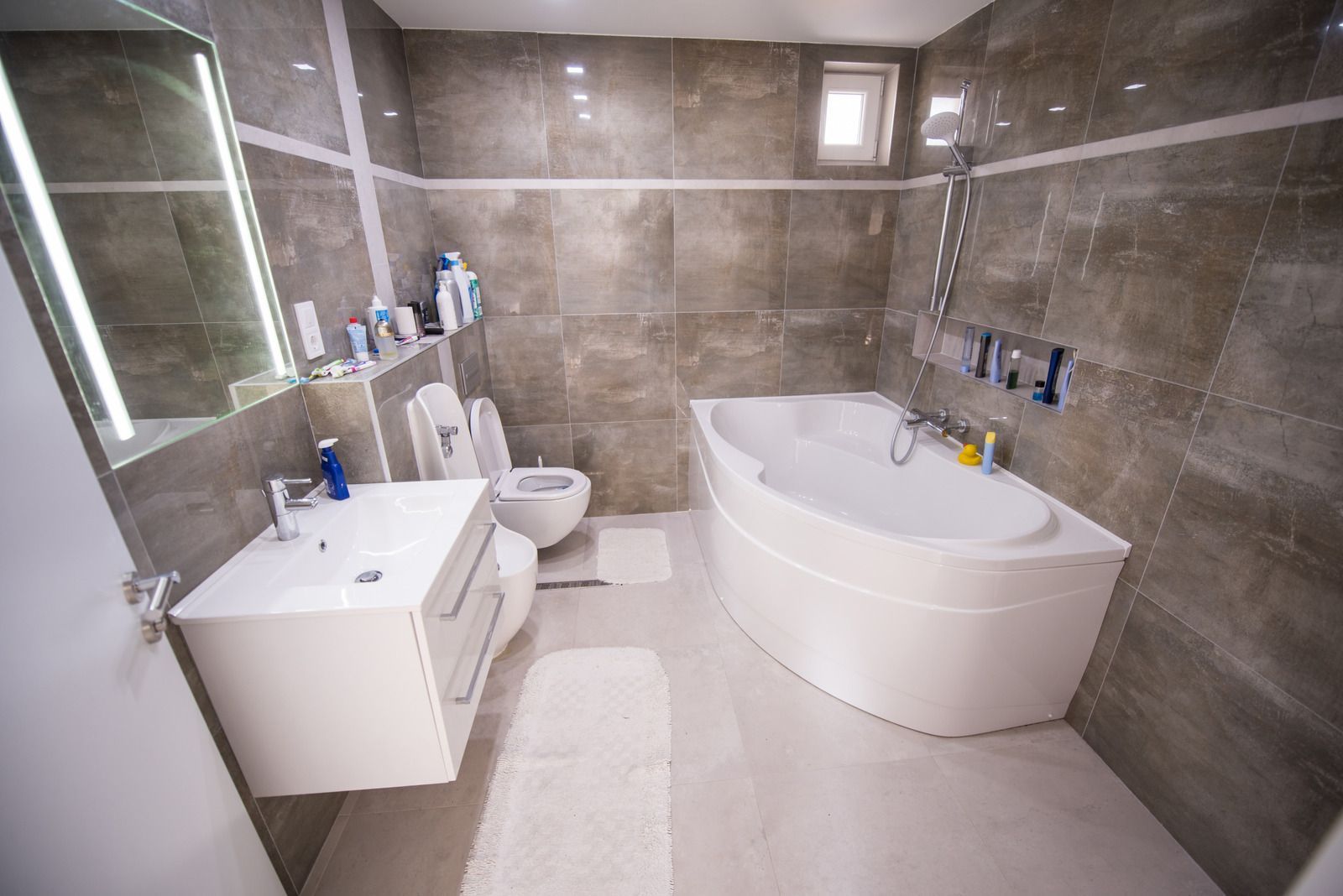 A bathroom with a tub , sink , toilet and mirror.