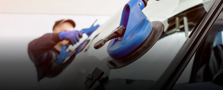 A person using a suction cup tool to remove a car windshield | CARSTAR Oakville West