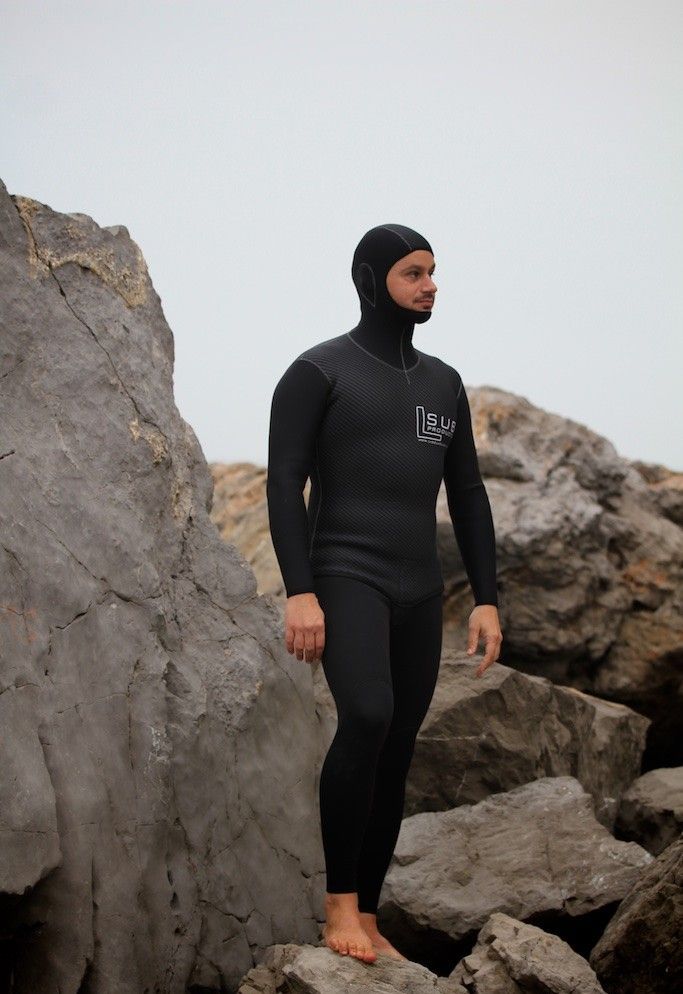 Un uomo con una muta è in piedi su una roccia.