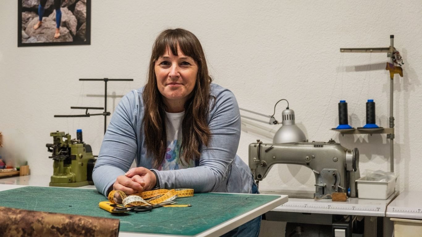 Una donna è seduta a un tavolo davanti a una macchina da cucire.