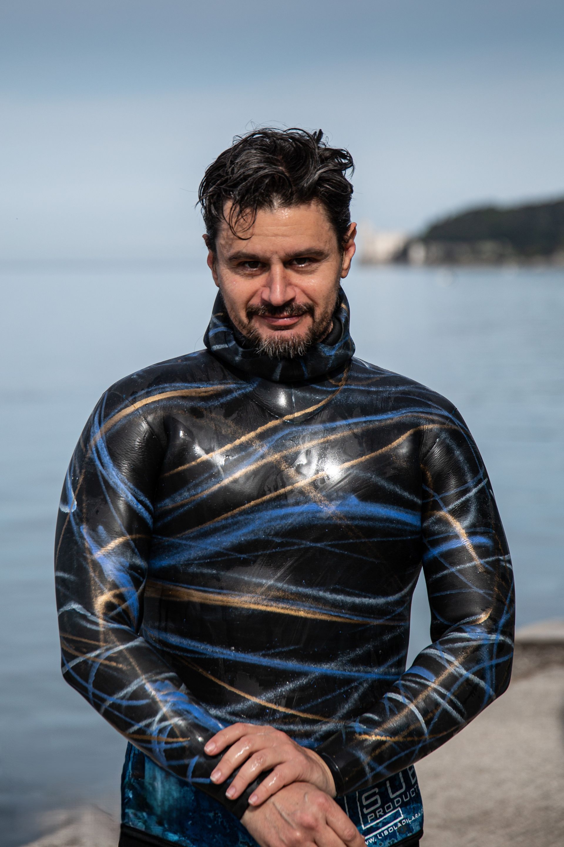 Un uomo con una muta è in piedi di fronte all'oceano.