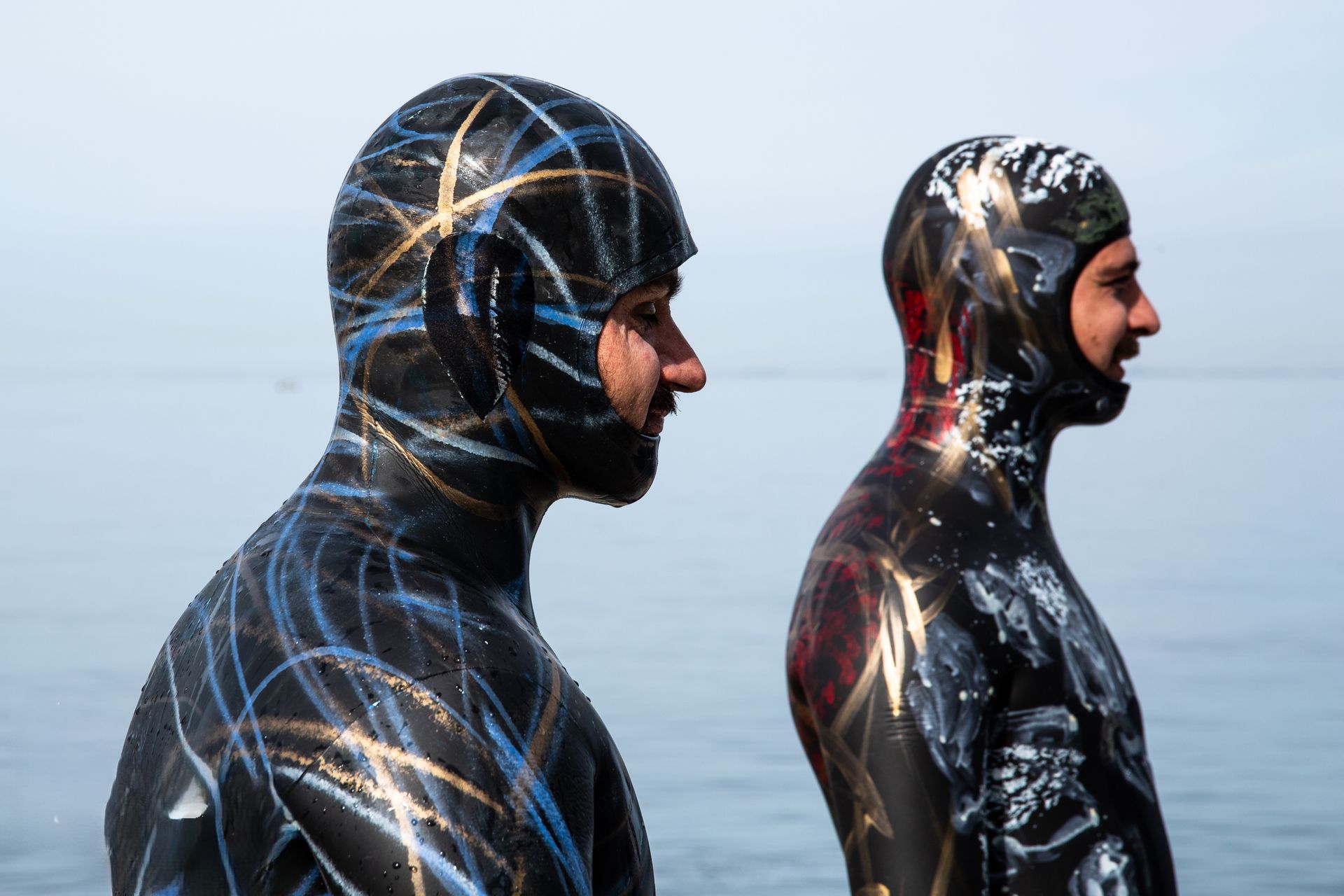 Due uomini in muta sono in piedi uno accanto all'altro nell'acqua.