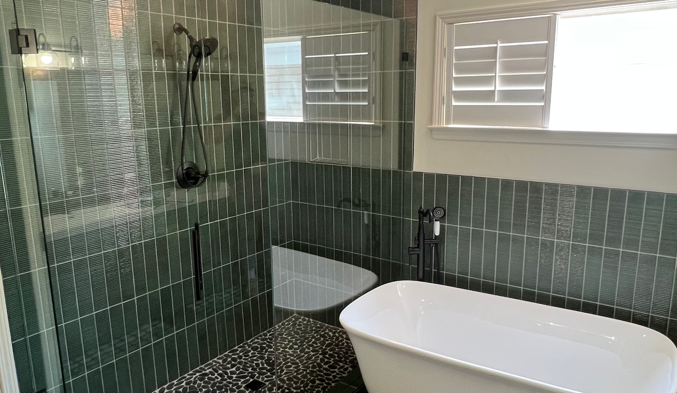 A bathroom with a tub , toilet , shower and window.