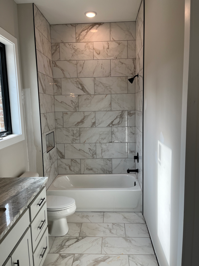 A bathroom with a toilet , bathtub and shower.