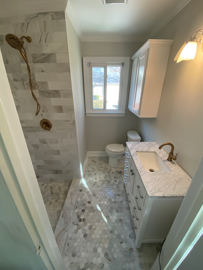 A bathroom with a sink , toilet , shower and window.
