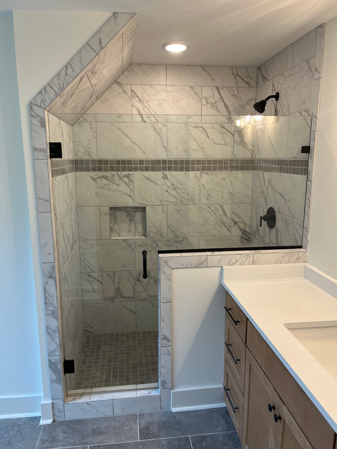 A bathroom with a walk in shower and a sink.