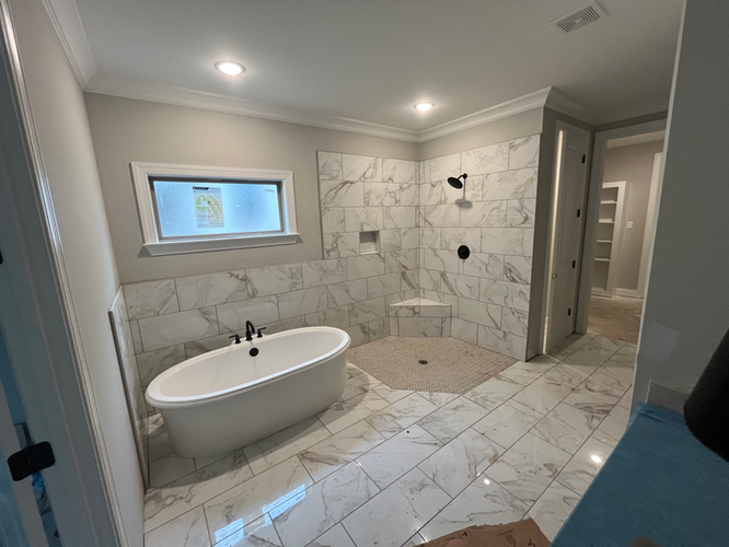 A bathroom with a tub , shower , and window.