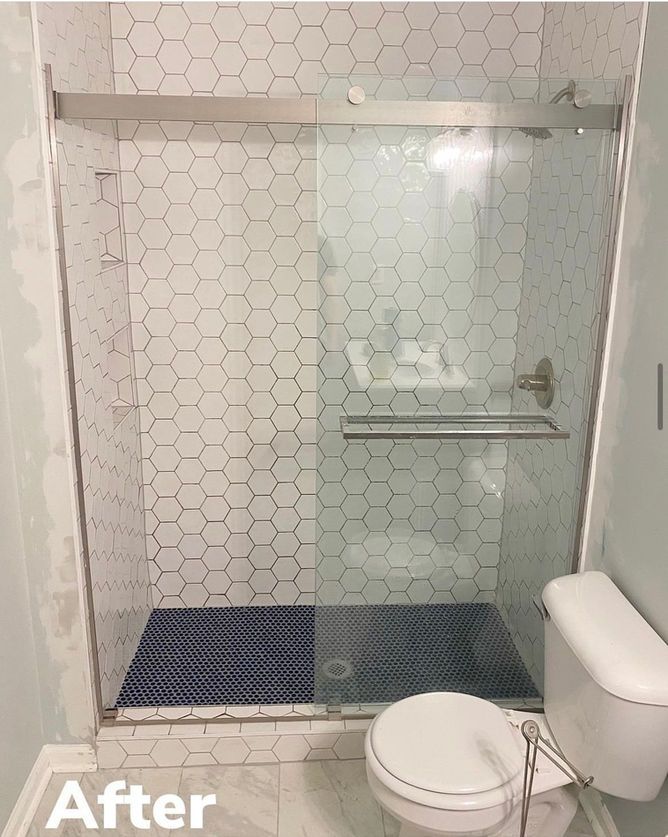 A bathroom with a toilet , shower , and honeycomb tiles.