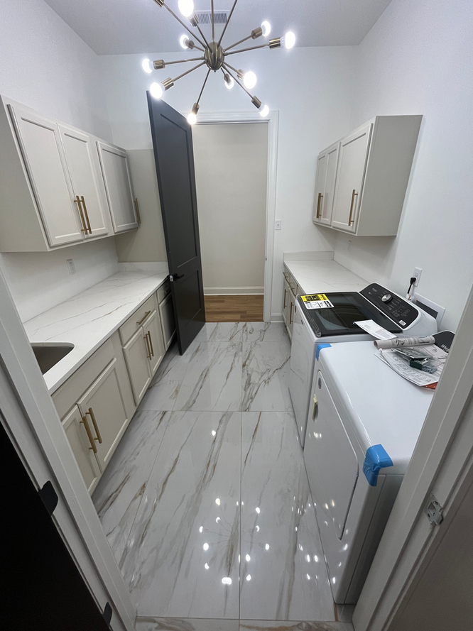 A kitchen with white cabinets and a marble floor