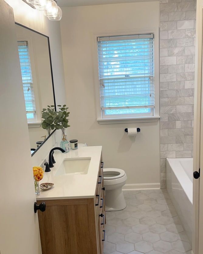 A bathroom with a sink , toilet , mirror and bathtub.