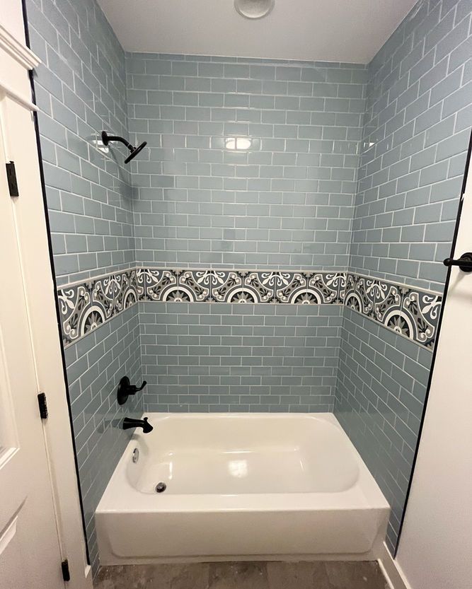A bathroom with blue subway tiles and a bathtub.