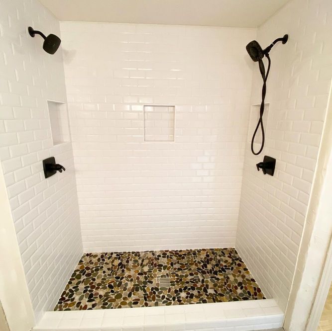 A shower with two shower heads and a stone floor