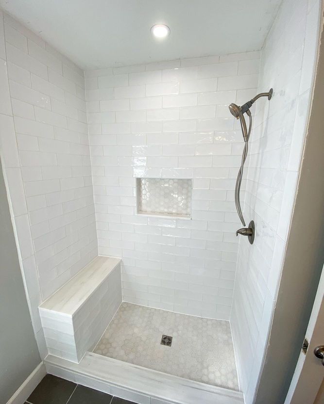 A shower with a bench and a shower head in a bathroom.