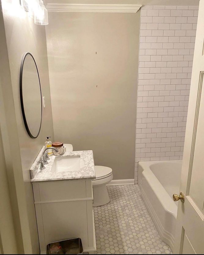 A bathroom with a toilet , sink , mirror and bathtub.