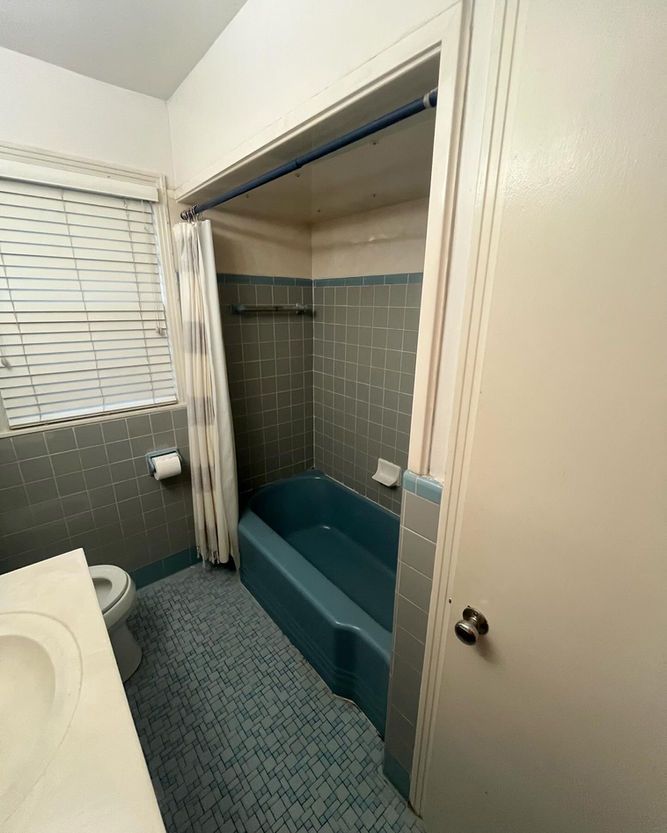 A bathroom with a blue bathtub and a toilet