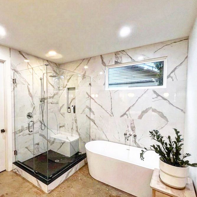 A bathroom with marble walls and a tub and shower