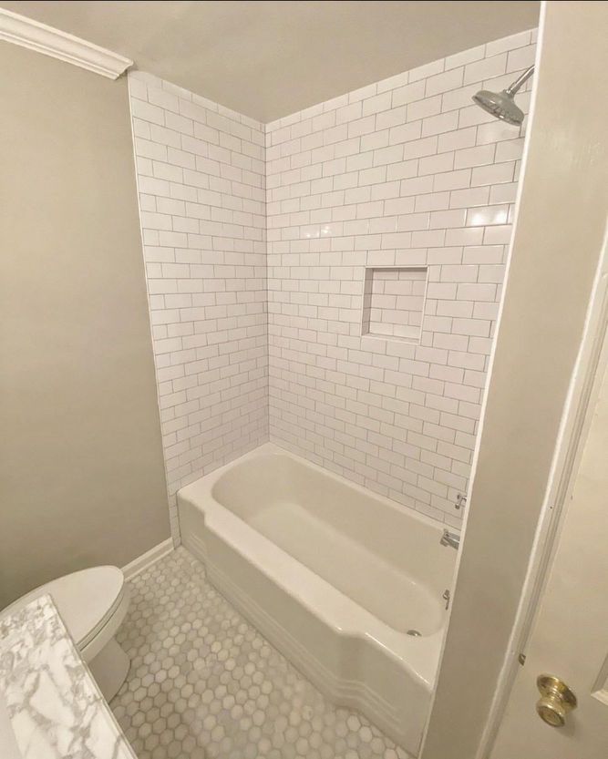 A bathroom with a bathtub , toilet and shower.