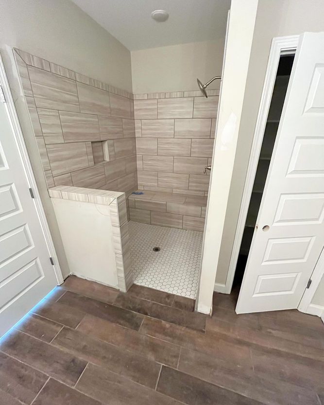 A bathroom with a walk in shower and a wooden floor.