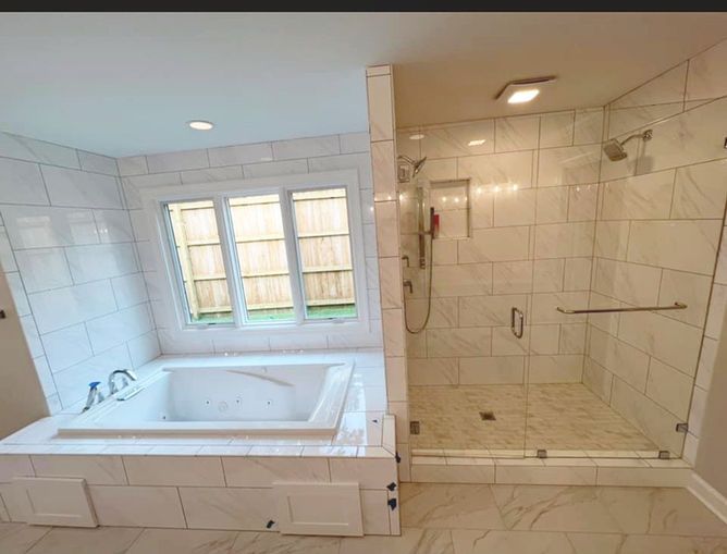 A bathroom with a tub , shower , and window.
