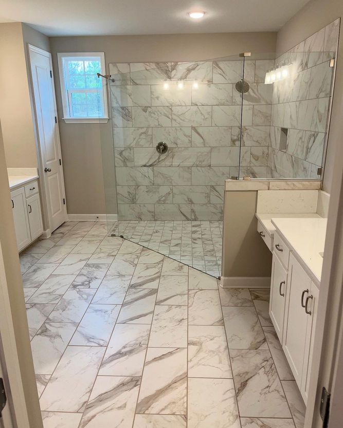 A bathroom with marble tile floors and a walk in shower.