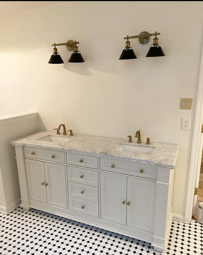 A bathroom with two sinks and two lights on the wall.