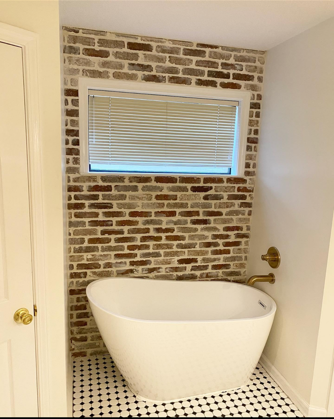 A bathtub in a bathroom with a brick wall