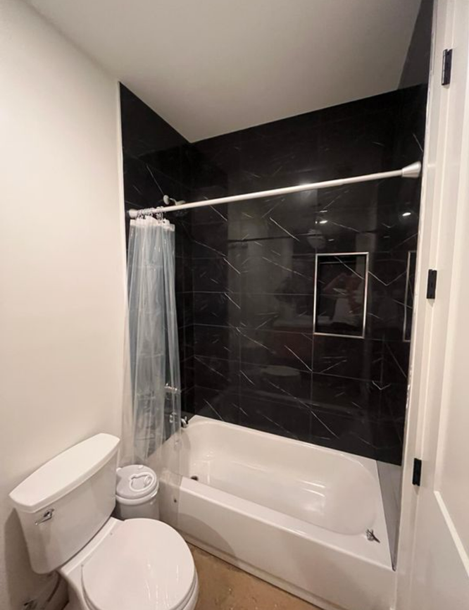 A bathroom with a toilet , tub and shower.