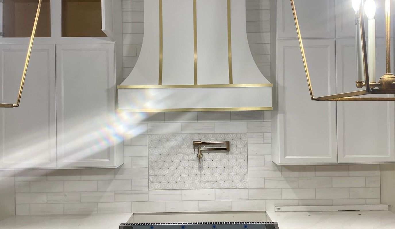 A kitchen with white cabinets and a stove top oven.