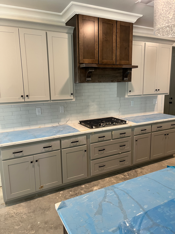 A kitchen with white cabinets and a stove top oven.