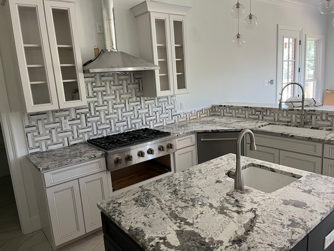 A kitchen with granite counter tops , stainless steel appliances , and white cabinets.