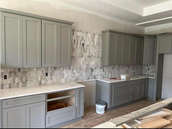 A kitchen with gray cabinets and white counter tops is being remodeled.