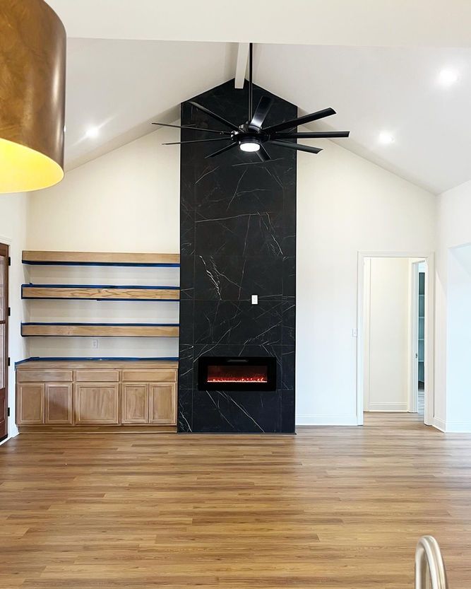 A living room with a fireplace and a ceiling fan.