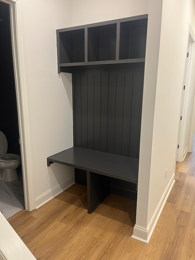 A hallway with a bench and shelves in a house.