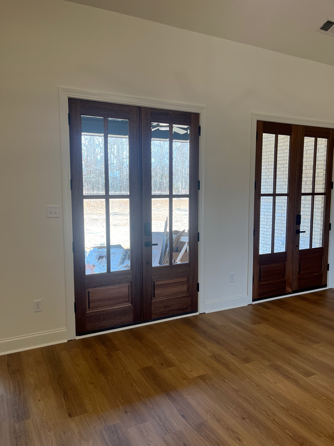 A living room with hardwood floors and two french doors.