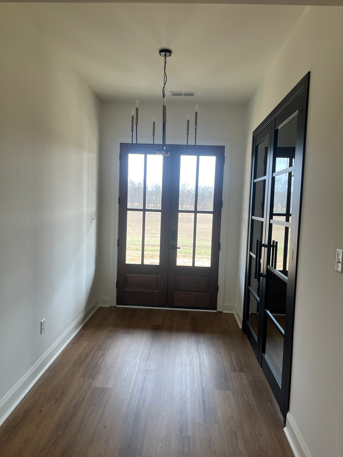 A hallway with hardwood floors and a chandelier hanging from the ceiling.