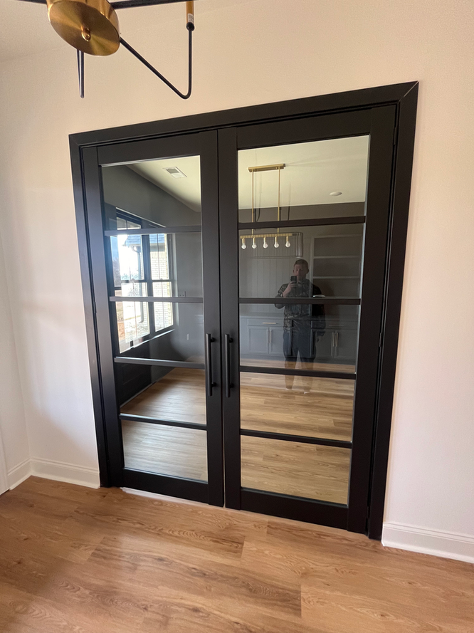 A man is taking a picture of himself in a room with sliding glass doors.