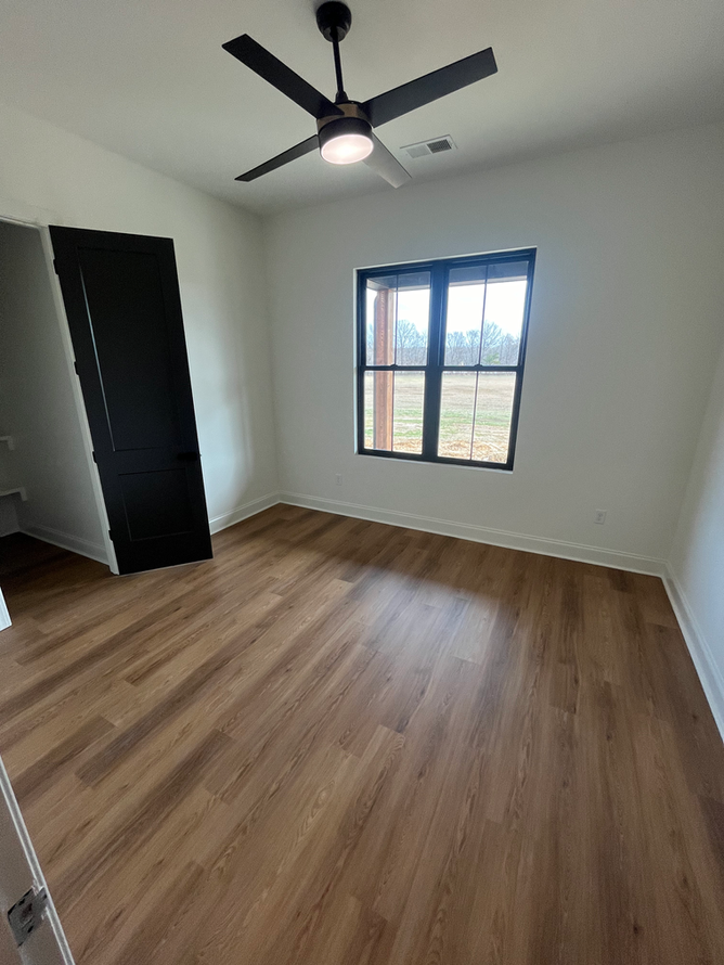 A bedroom with hardwood floors and a ceiling fan.