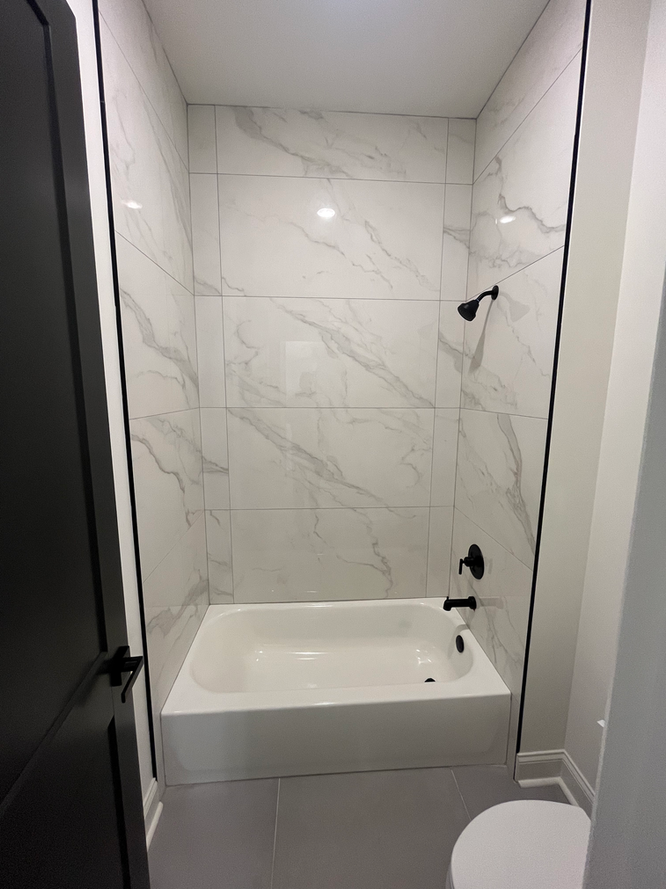 A bathroom with a bathtub , toilet and shower.