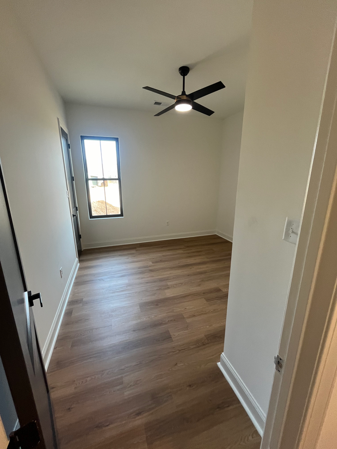 A bedroom with hardwood floors and a ceiling fan.