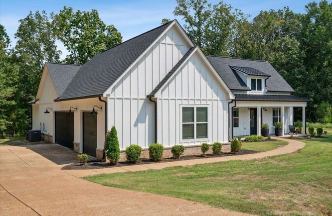 A white house with a black roof and a garage