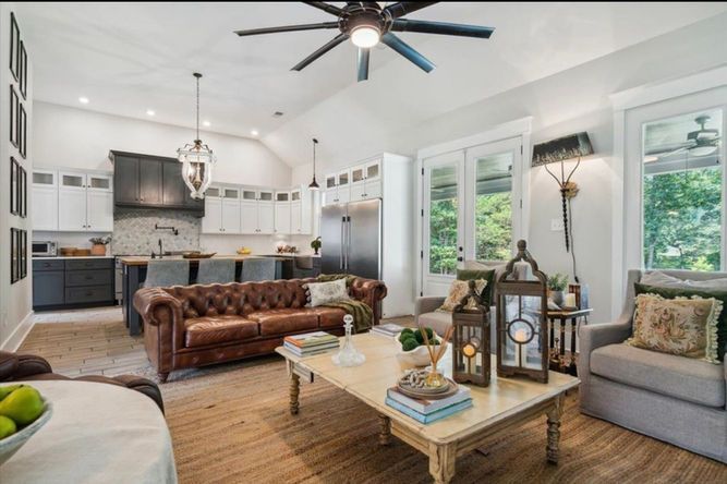 A living room with a couch , coffee table , chairs and a ceiling fan.