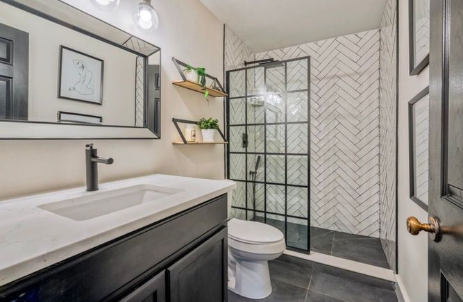 A bathroom with a toilet , sink , mirror and walk in shower.