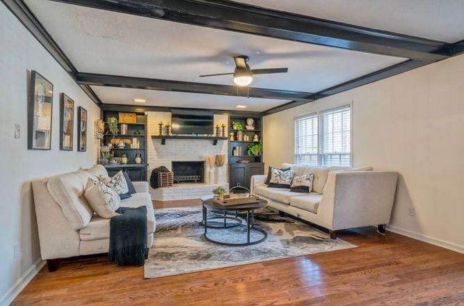 A living room with a couch , chair , coffee table and fireplace.