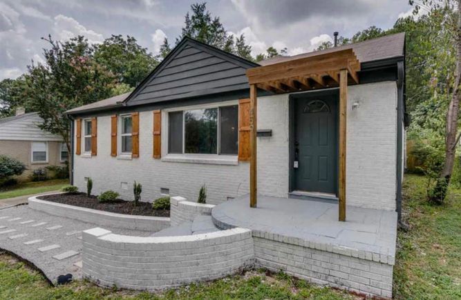 A white brick house with a black door and shutters