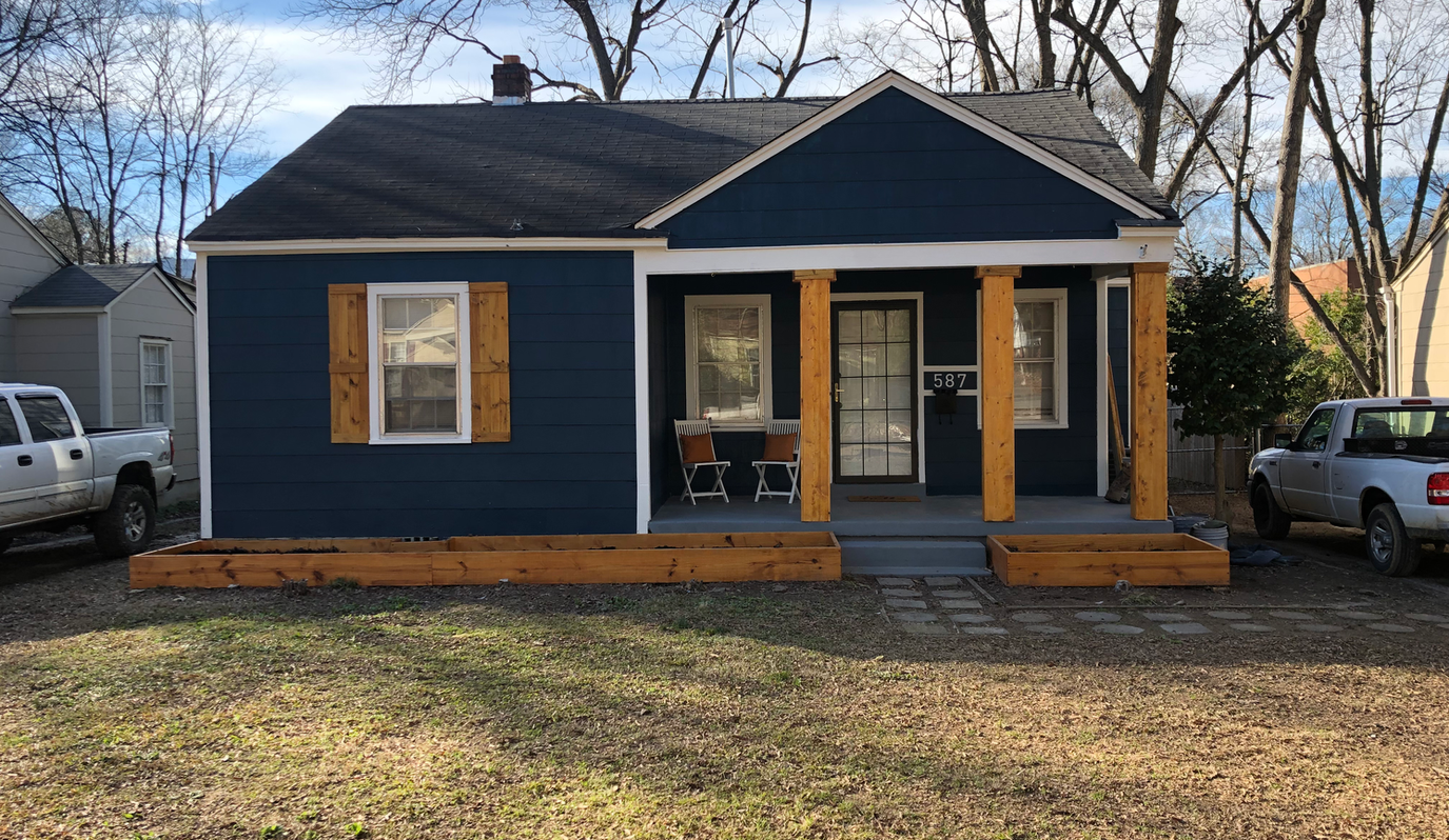 A blue house with a porch and a truck parked in front of it.