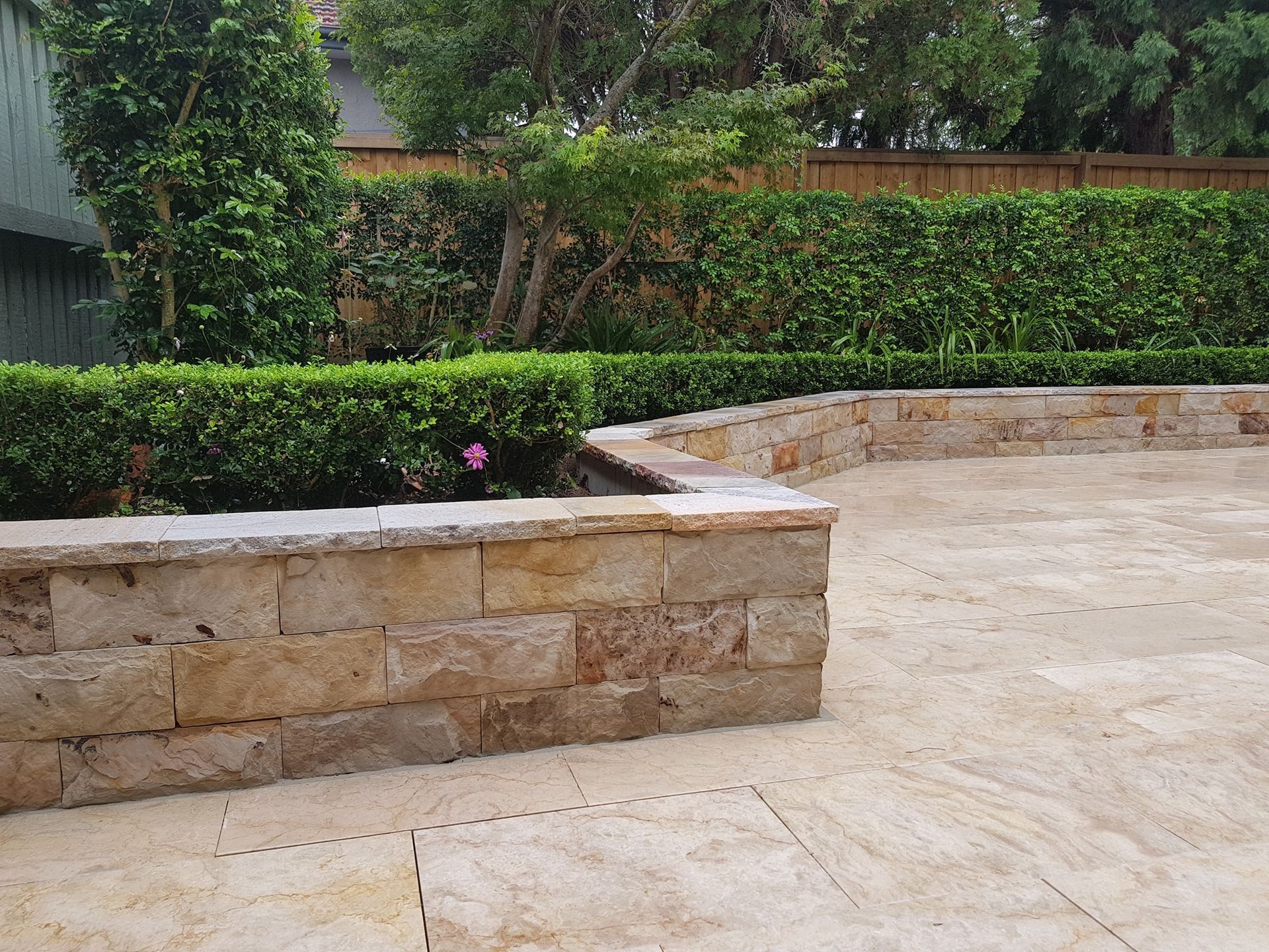 Stone Retaining Wall With Greenery and Paved Patio — Total Perfection In Gosford, NSW
