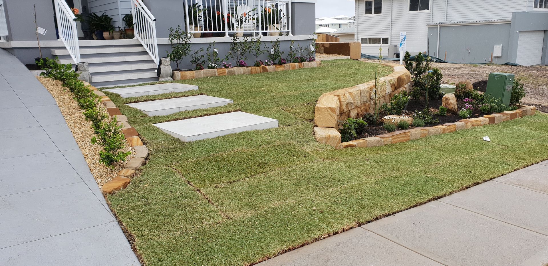 A Landscaped Front Yard With a Stone Retaining Wall, Stepping Stones — Total Perfection In Gosford, NSW