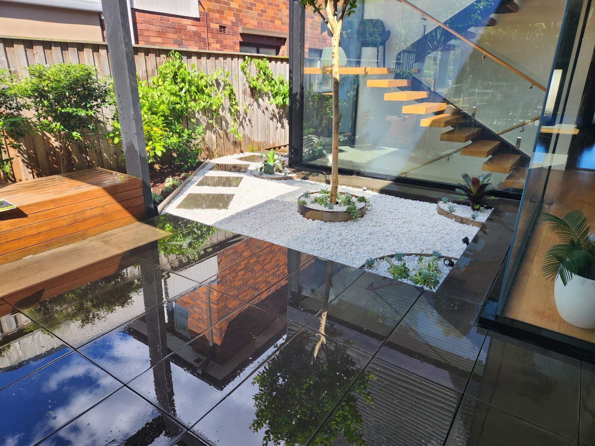 Modern Courtyard With Glass Walls and Reflecting Wet Tiles — Total Perfection In Kincumber, NSW