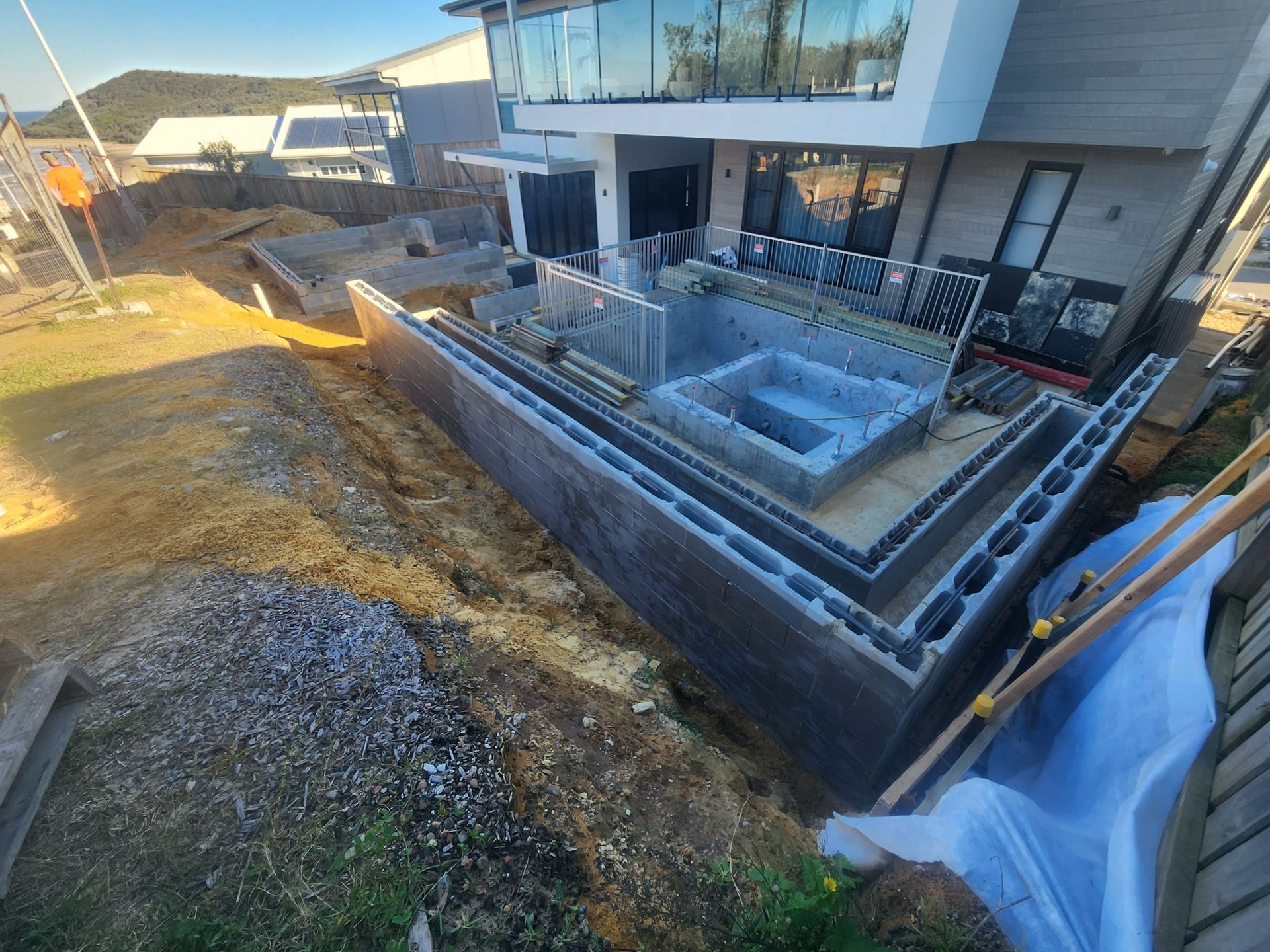 Concrete Block Walls Forming a Tiered Foundation Next to a Modern House — Total Perfection In Kariong, NSW