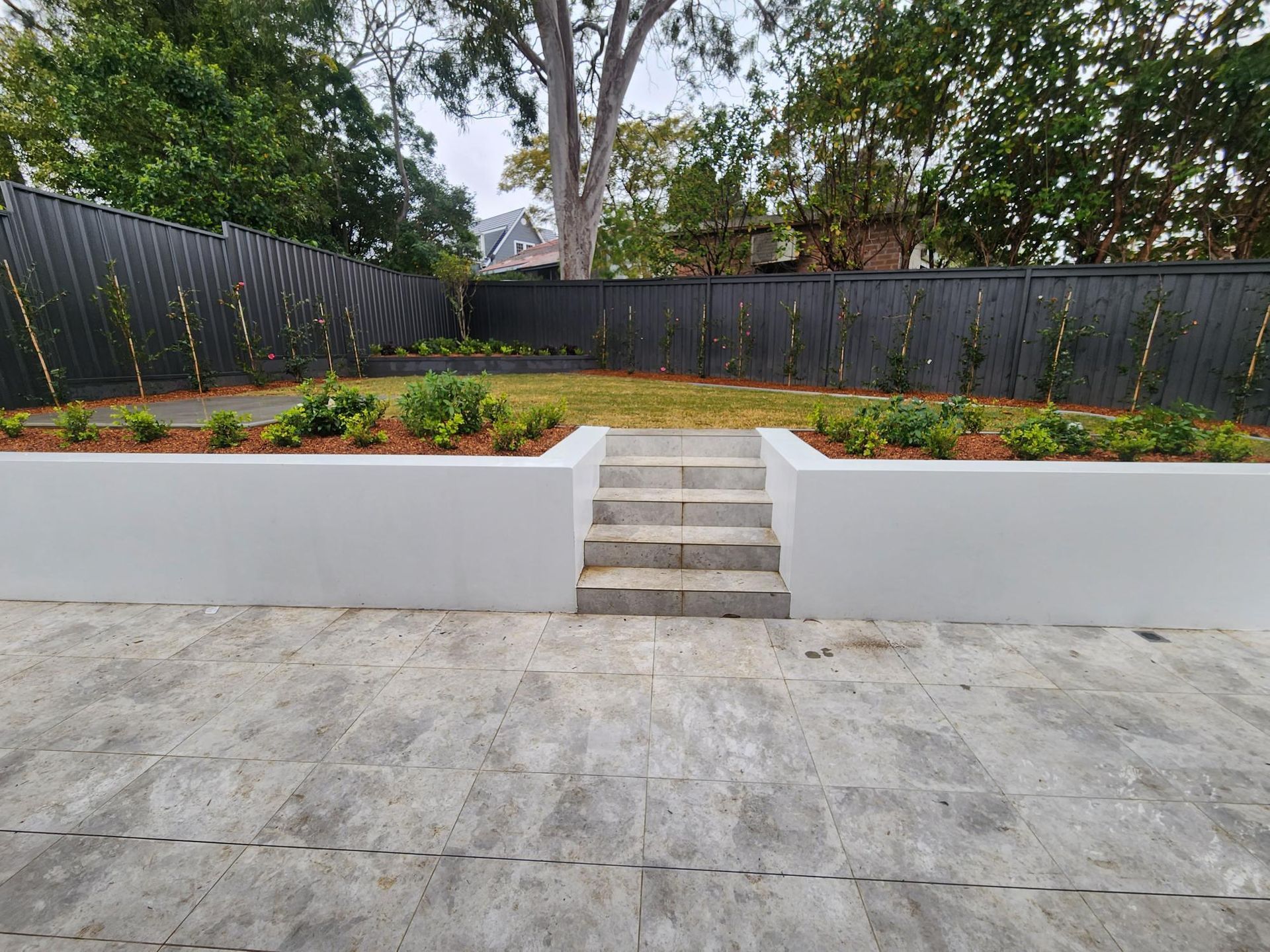 Backyard With White Retaining Walls and Black Fence — Total Perfection In Avoca Beach, NSW